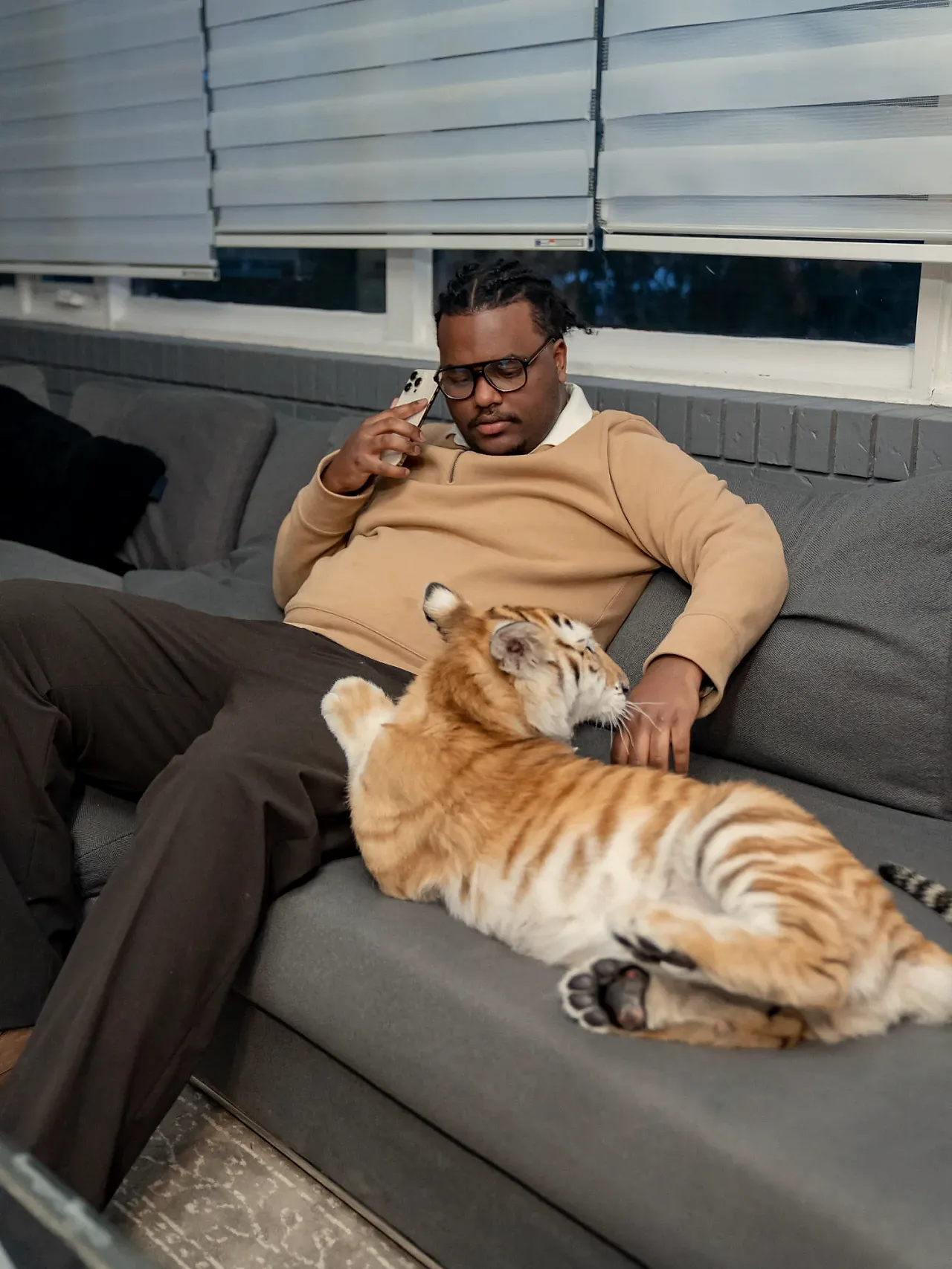 Negus taking a call at home, a tiger cub stretched out beside him.